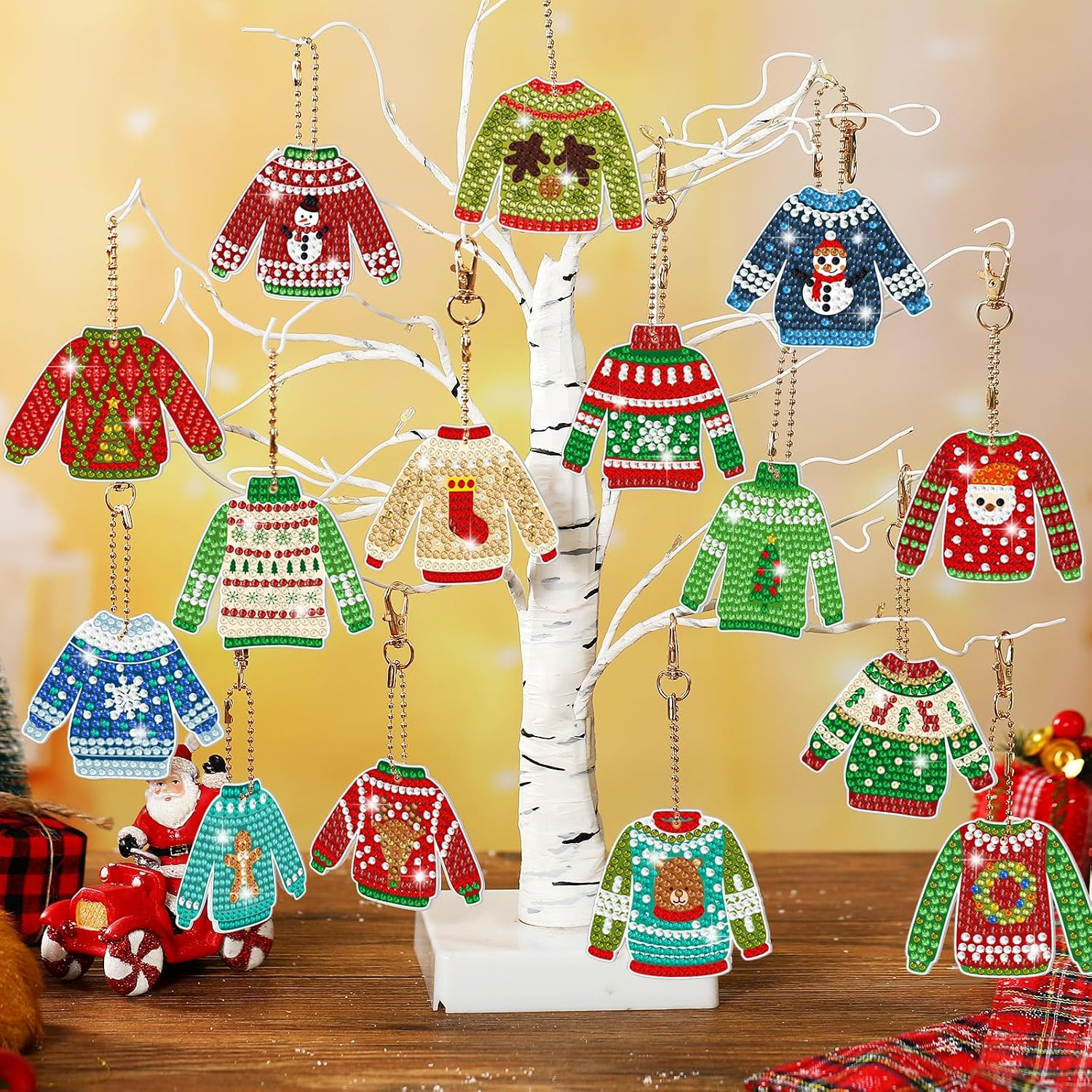 Bunte Weihnachtspullover-Ornamente hängen an einem kleinen weißen Baum.
