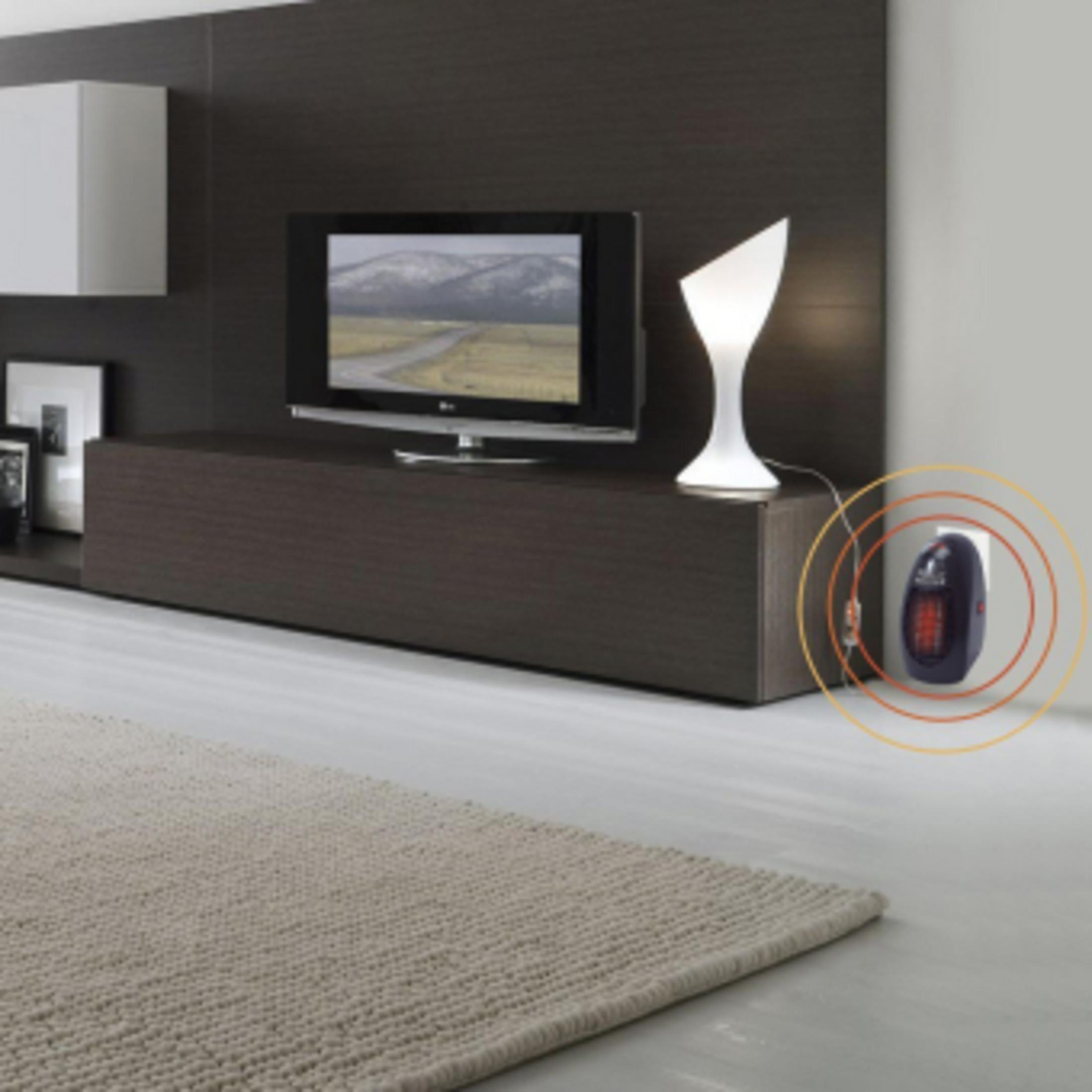 Ein kleiner Wandheizer ist in einer Steckdose in einem modernen Wohnzimmer eingesteckt.