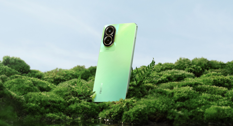 Un smartphone verde claro se encuentra en el suelo cubierto de musgo bajo un cielo despejado.