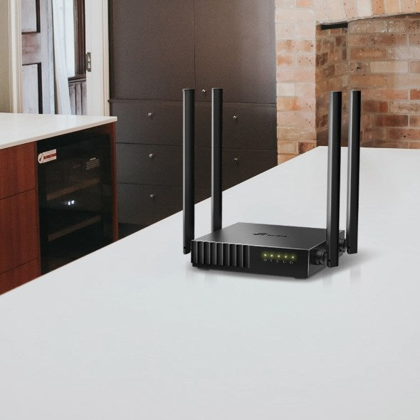 Czarny router Wi-Fi z czterema antenami stoi na białym blacie kuchennym.