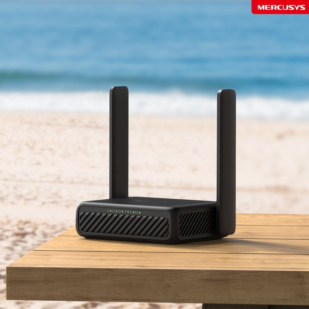 Czarny router Wi-Fi z dwiema antenami na drewnianym stole na tle plaży i morza.