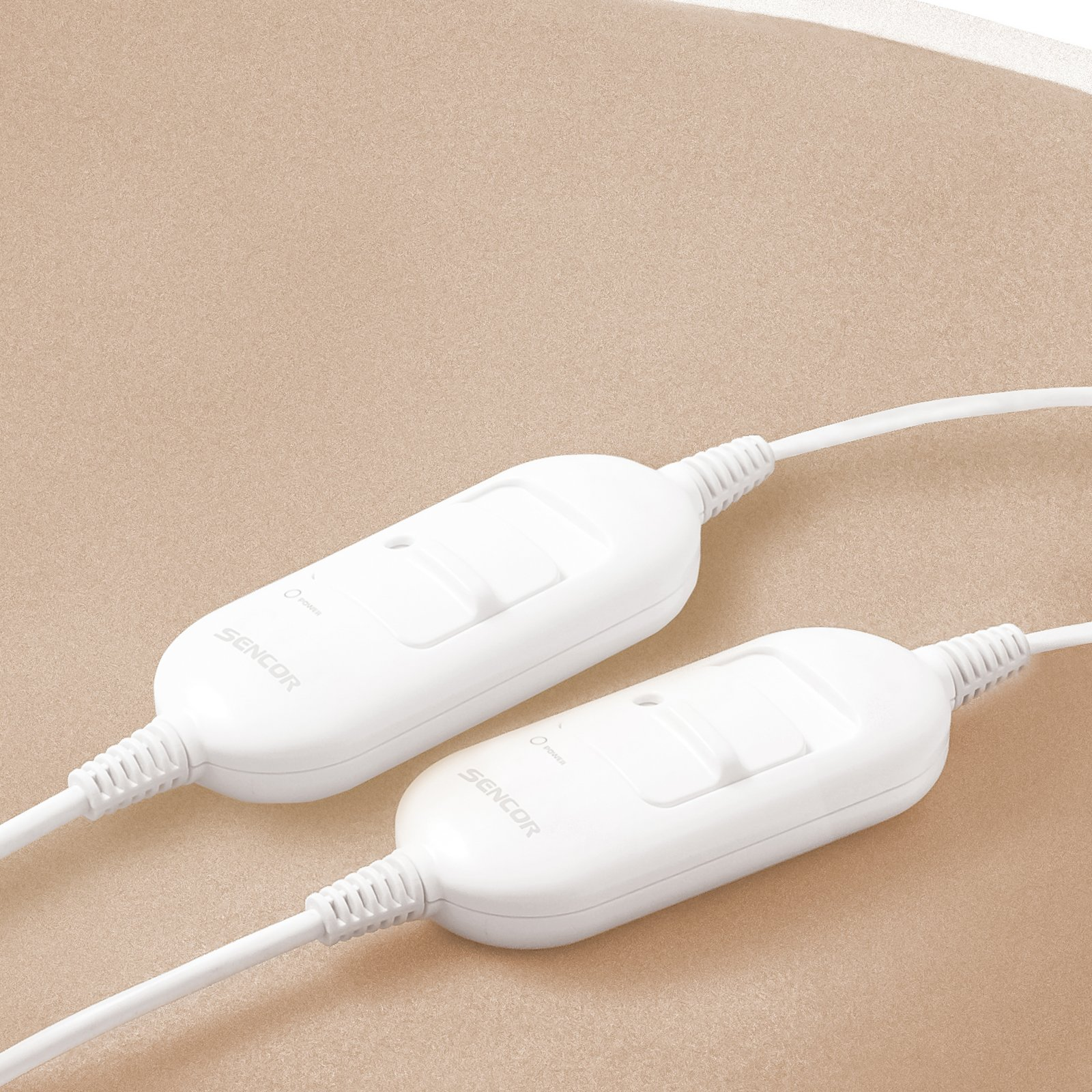 Dos mandos a distancia de cable Sencor blancos con interruptores deslizantes sobre superficie beige.