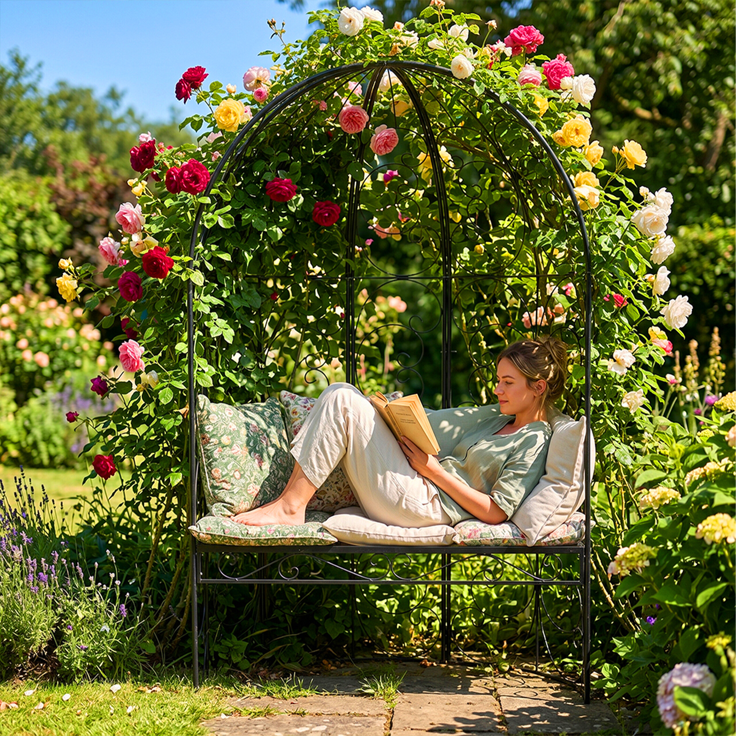 Eine Frau liest ein Buch auf einer Eisenbank, die von einem Bogen aus bunten Rosen umgeben ist.
