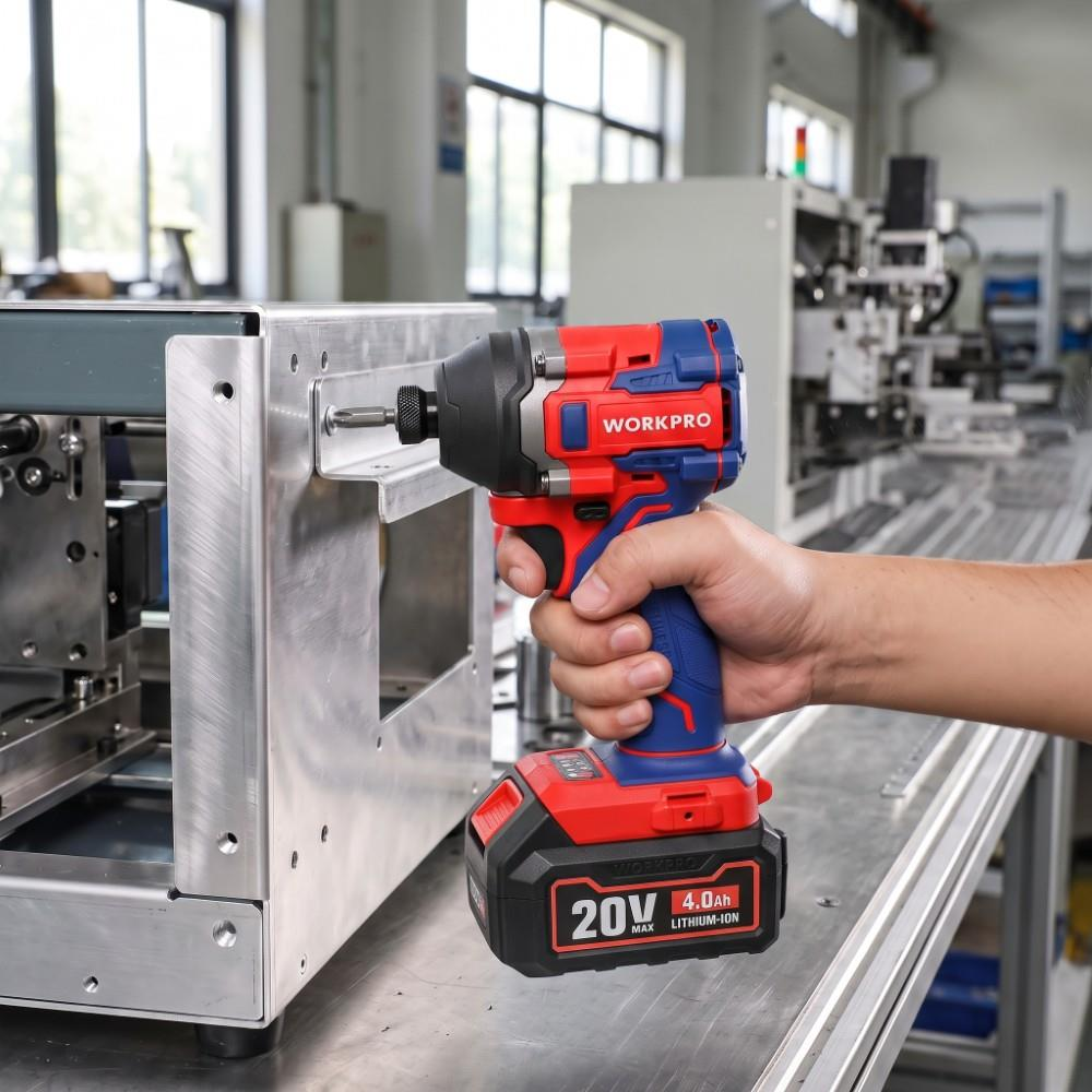Bir fabrika ortamında metal makineye karşı kırmızı ve mavi akülü darbeli matkap tutan bir el.