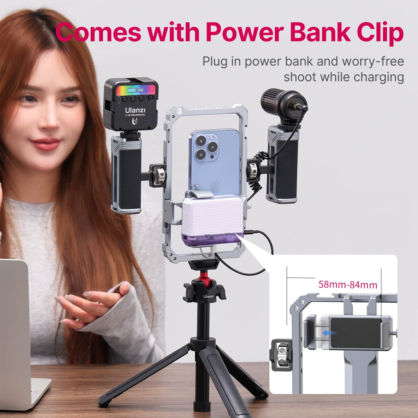 Een vrouw zit naast een smartphonerig op een statief, uitgerust met een lamp, microfoon en powerbank.