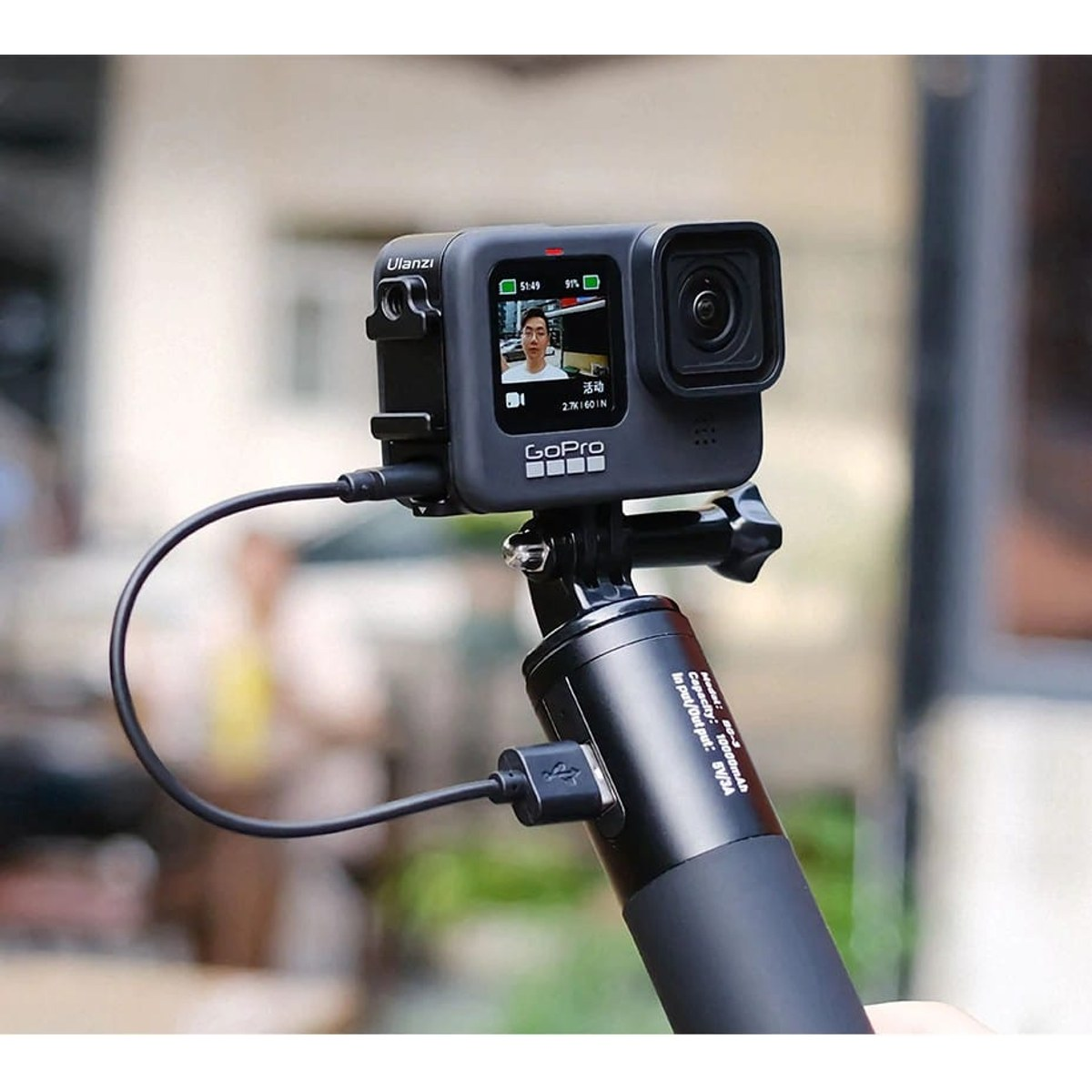 Caméra GoPro montée sur une poignée, connectée avec un court câble de charge.