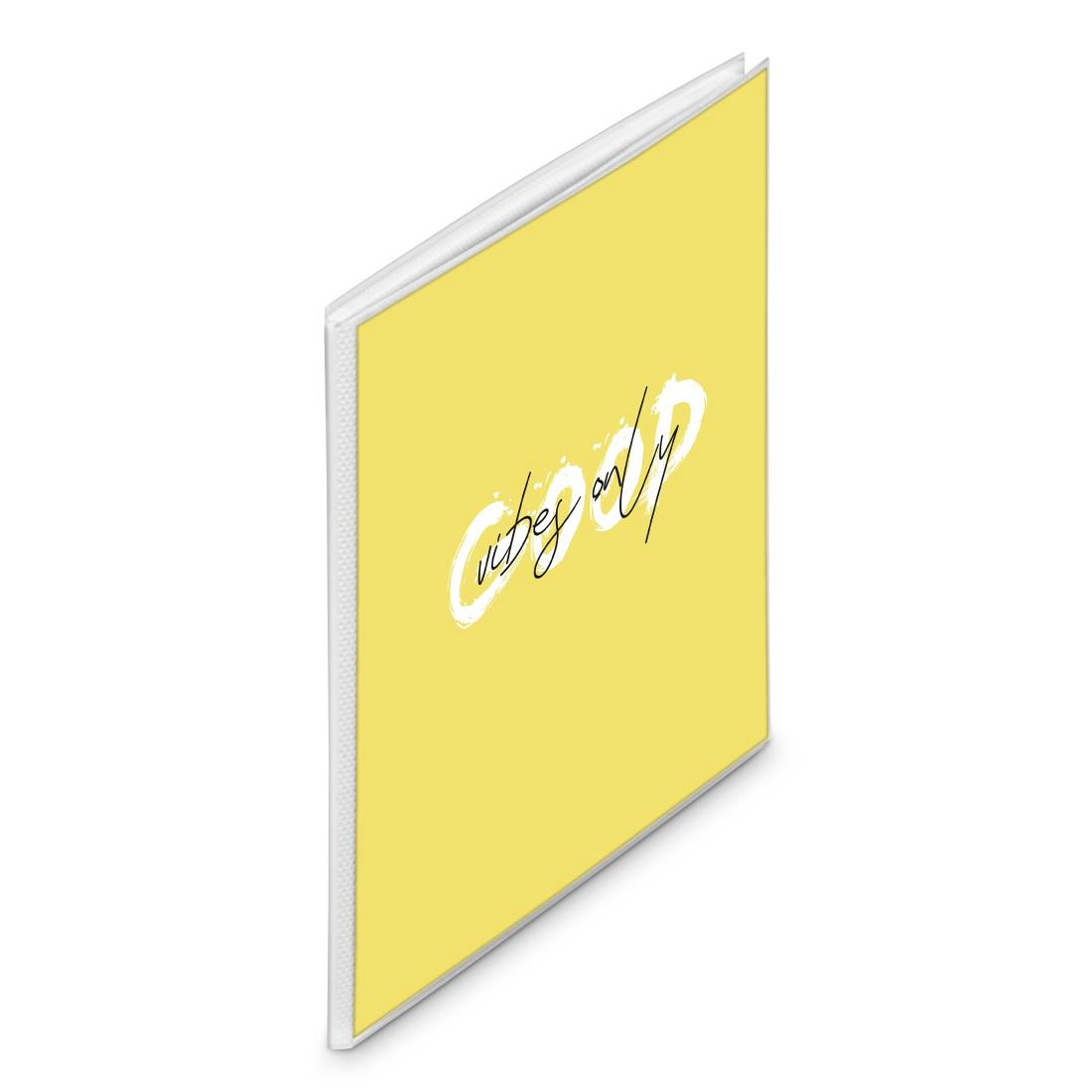 Ein gelbes Notizbuch mit weißem Rücken und dem schwarzen Text Vibes Only in geschwungener Schrift auf weißem Grund.