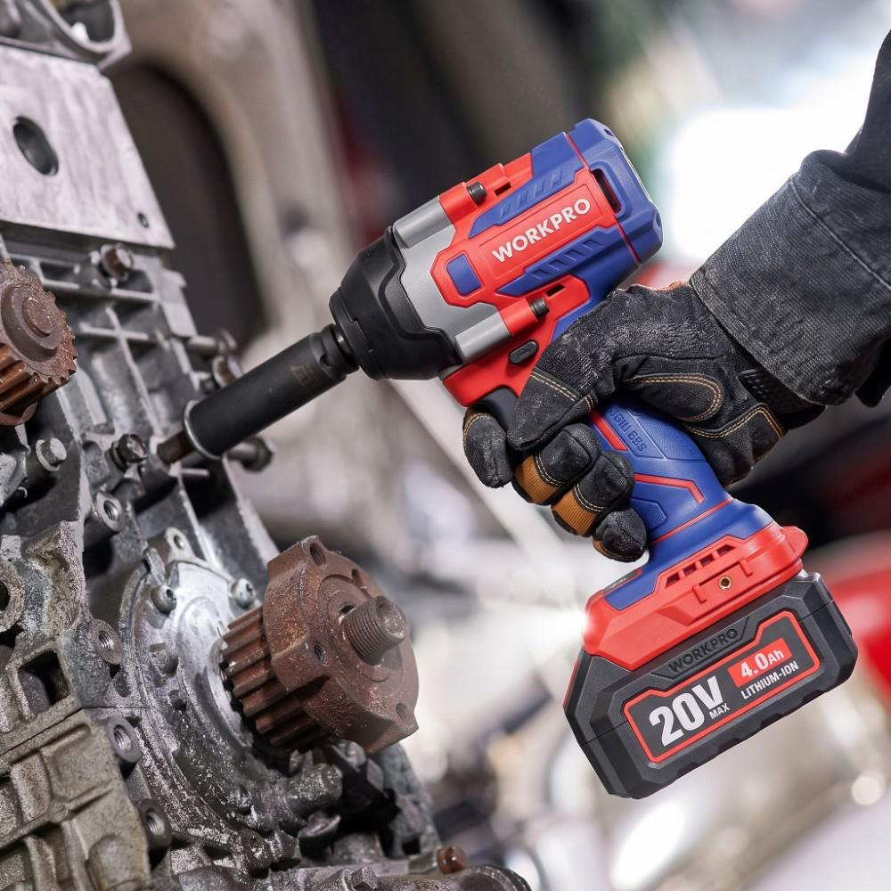Eldivenli bir el, makine motorunda çalışan mavi ve kırmızı 20V akülü darbe anahtarını tutuyor.