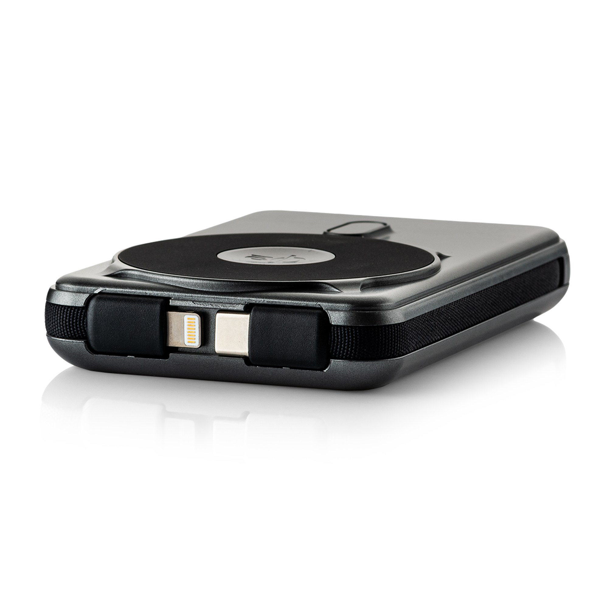 Eine schwarze Powerbank mit runder Auflagefläche und integrierten Kabeln liegt auf einer weißen Oberfläche.
