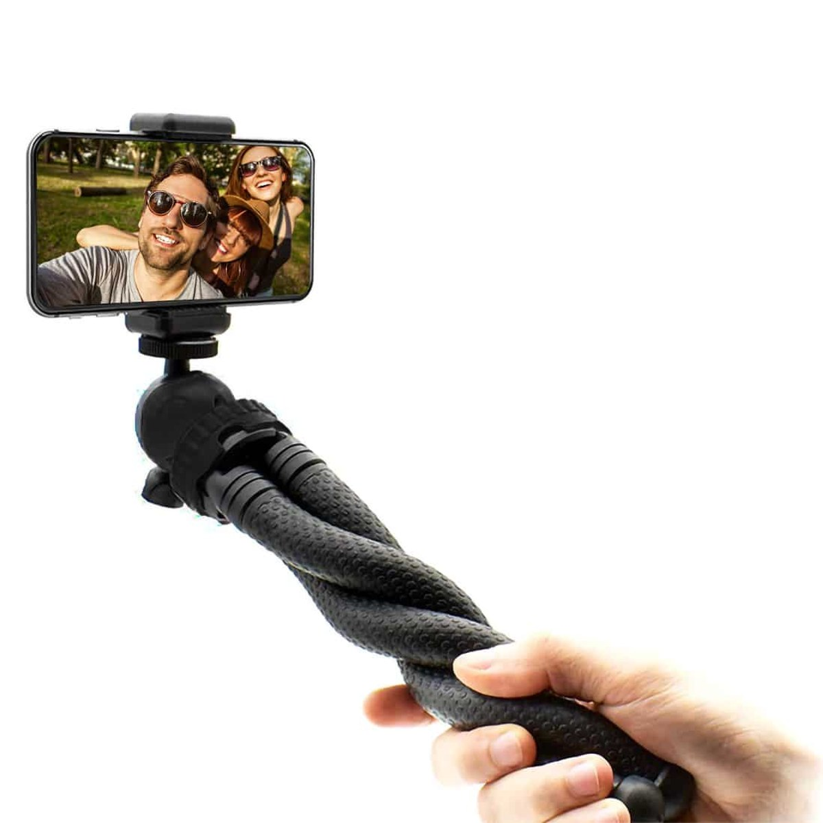A hand holds a flexible black tripod with a smartphone displaying a selfie of three smiling people.