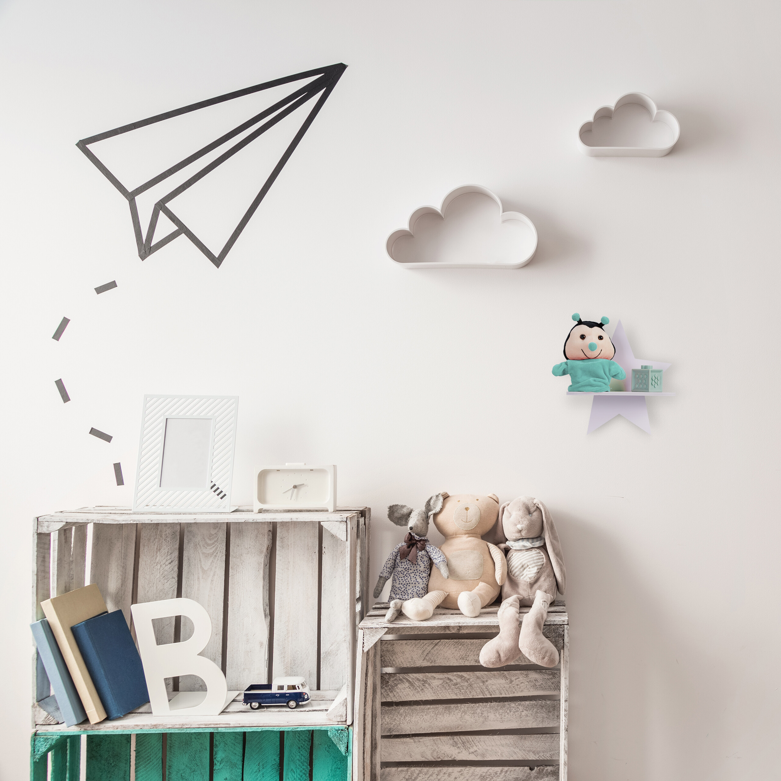 Kinderzimmerwand mit Flugzeug-Wandtattoo, Wolkenregalen, Plüschtieren auf Holzkisten und einem Star-Regal.
