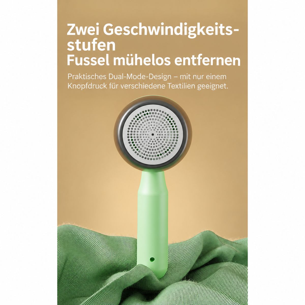 Grüner Fusselrasierer mit perforiertem Scherkopf steht auf grünem Stoff vor beigeem Hintergrund.
