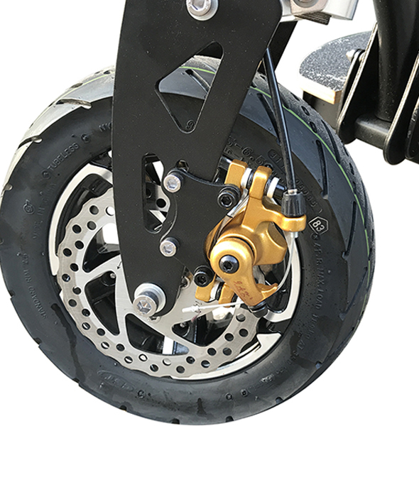Primer plano de la rueda delantera de un patinete eléctrico con freno de disco y pinza dorada.