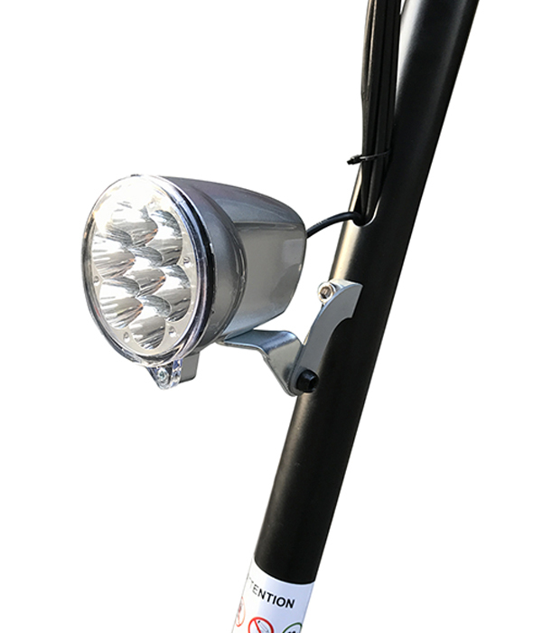 Un faro de bicicleta plateado está sujeto a un poste de metal negro.