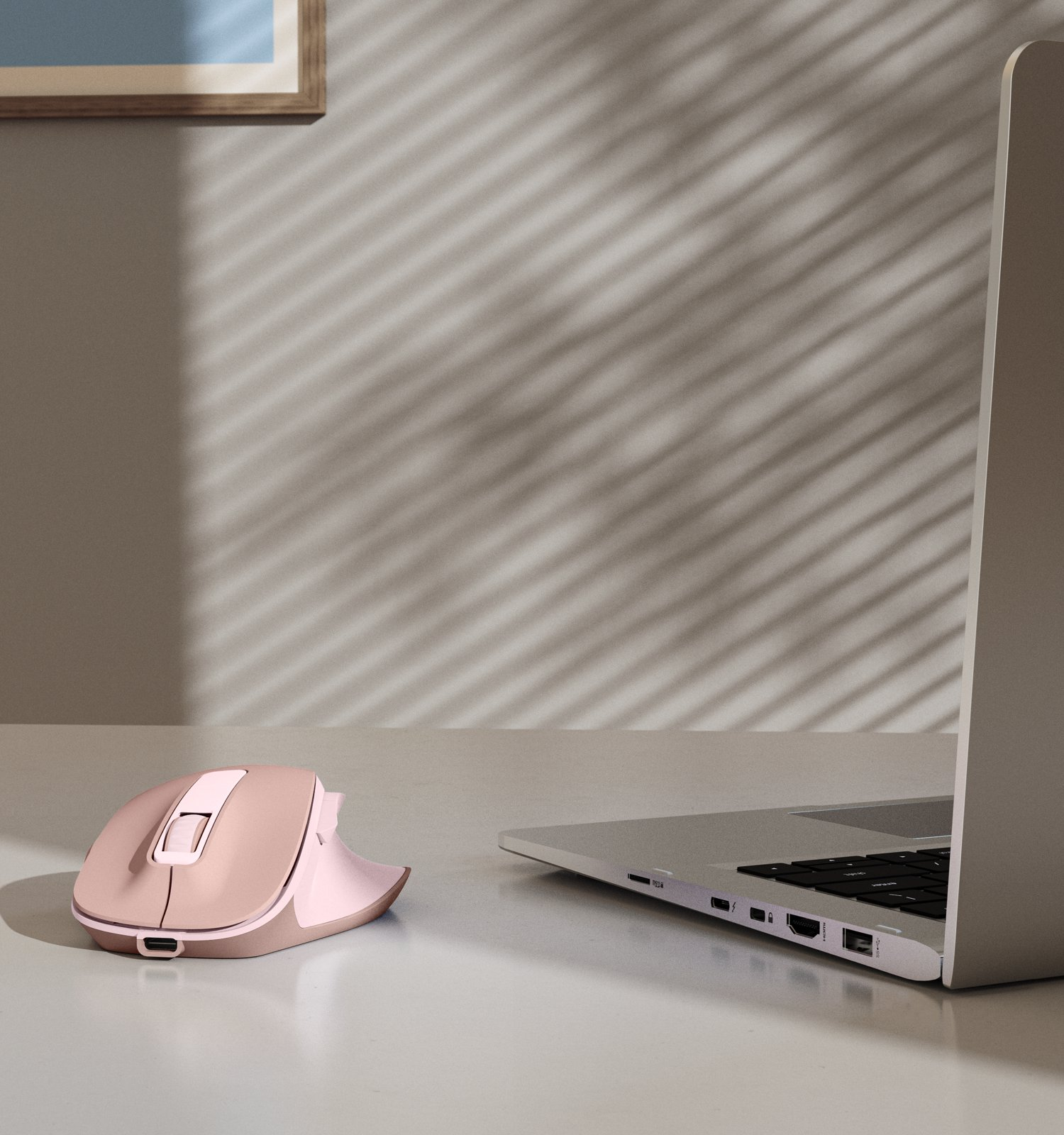 Mouse ergonomico rosa e computer portatile su scrivania chiara.