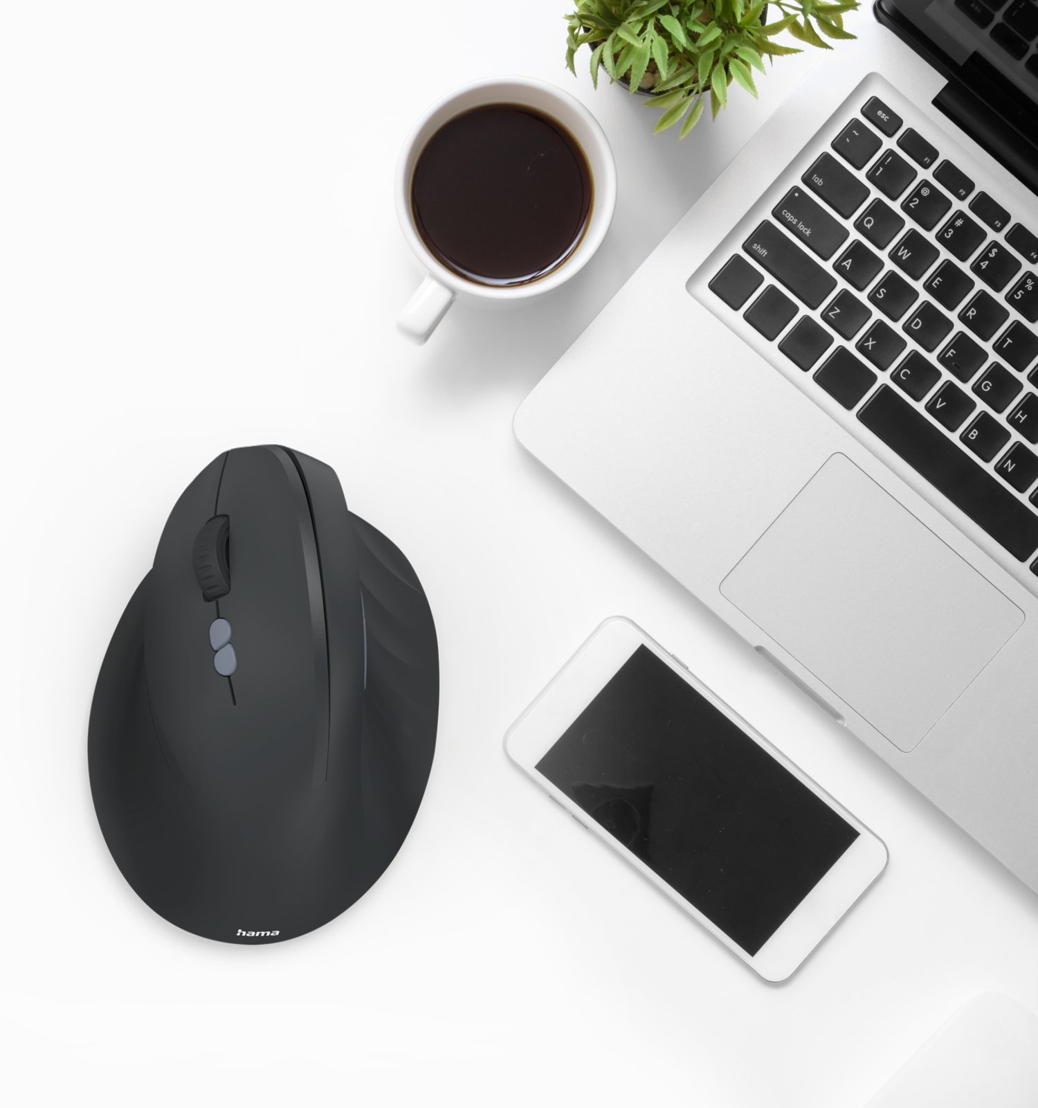 Vista superior de un escritorio con un ordenador portátil, ratón ergonómico negro, taza de café, smartphone y una planta.