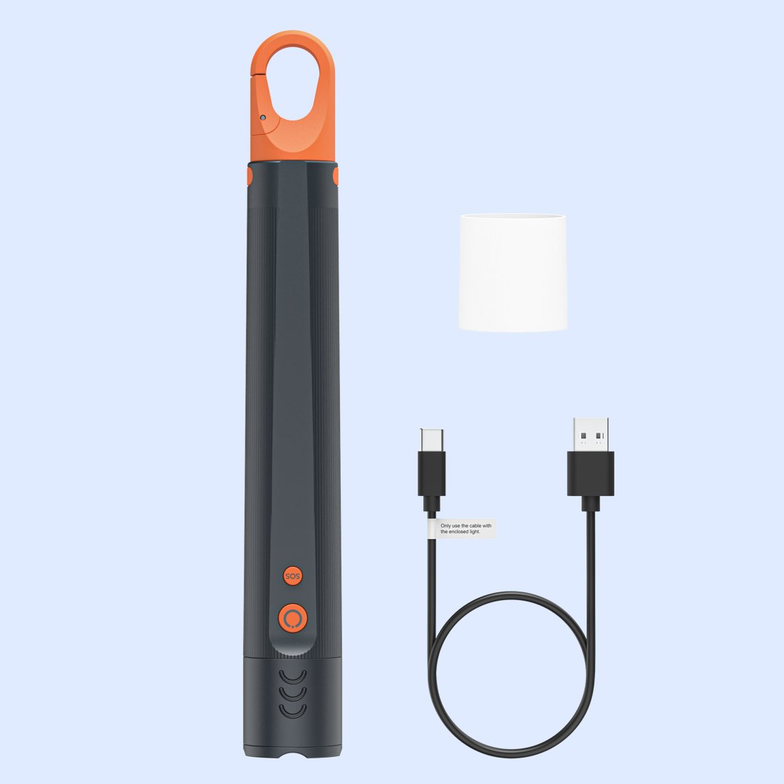 Linterna gris oscuro con mosquetón naranja, tapa blanca y cable USB negro sobre fondo azul claro.