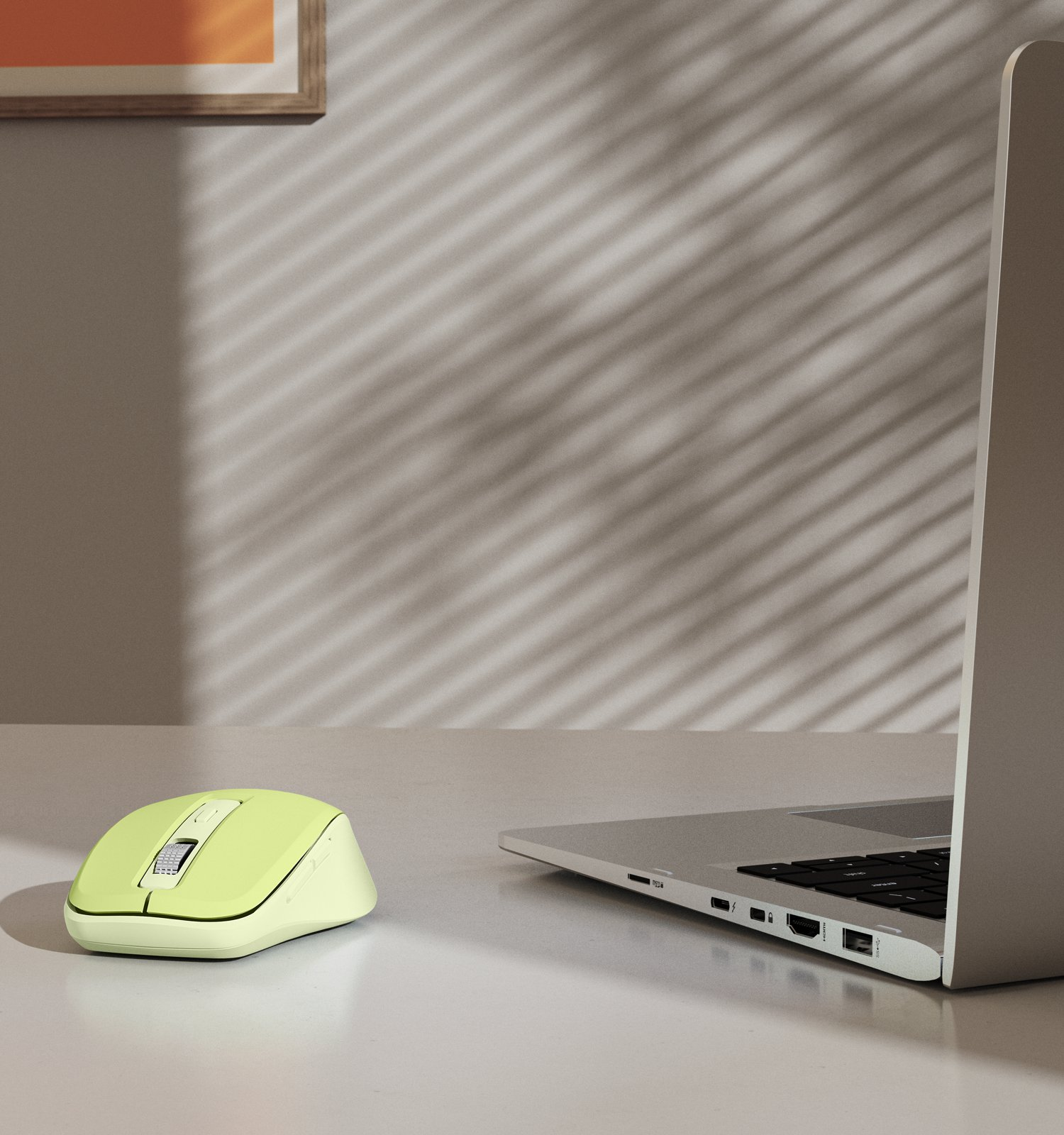 Limonkowa mysz komputerowa i laptop na białym biurku pod ścianą z wzorem cieni.