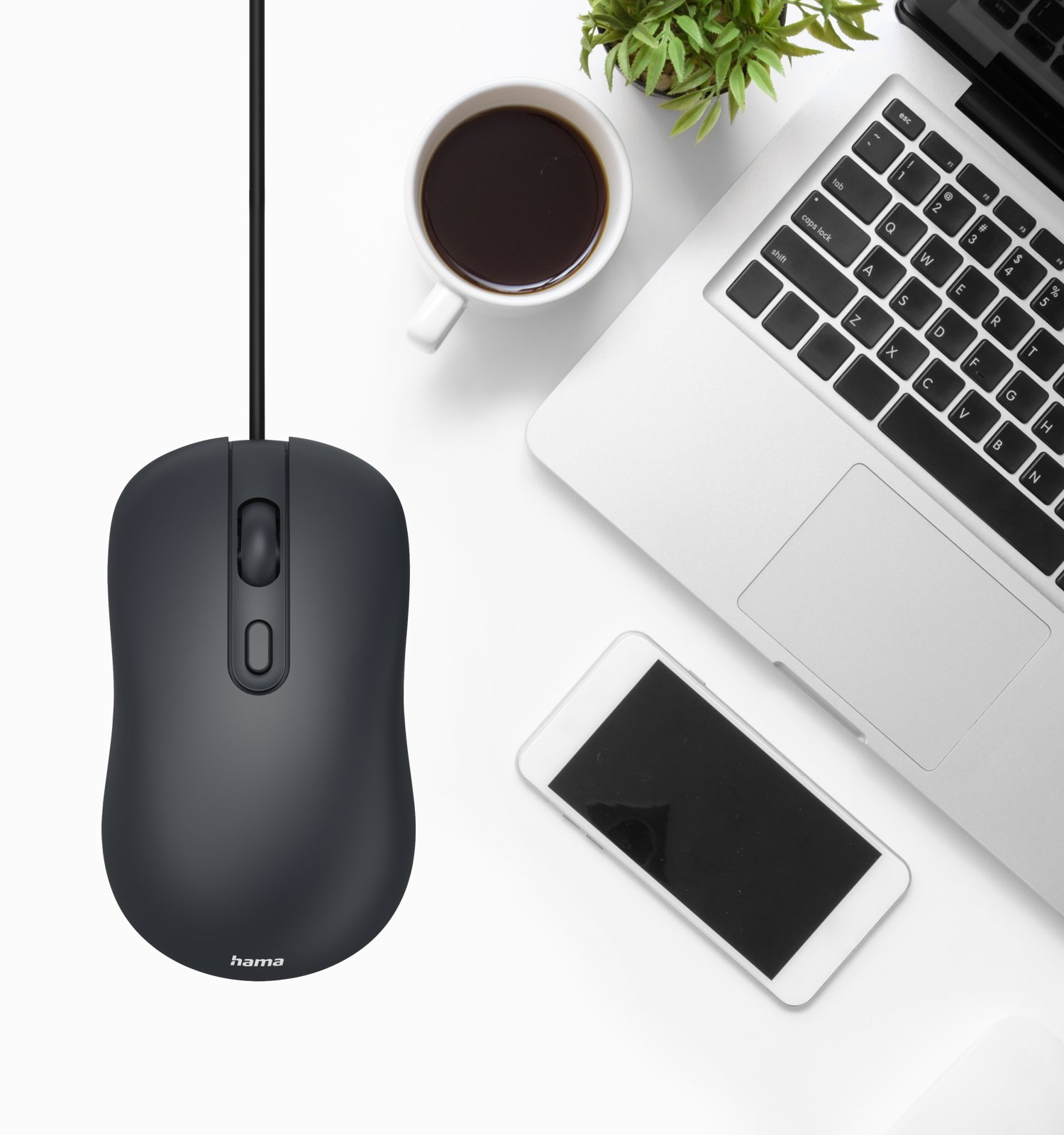 Un ratón Hama negro en un escritorio blanco con portátil, smartphone, taza de café y planta.