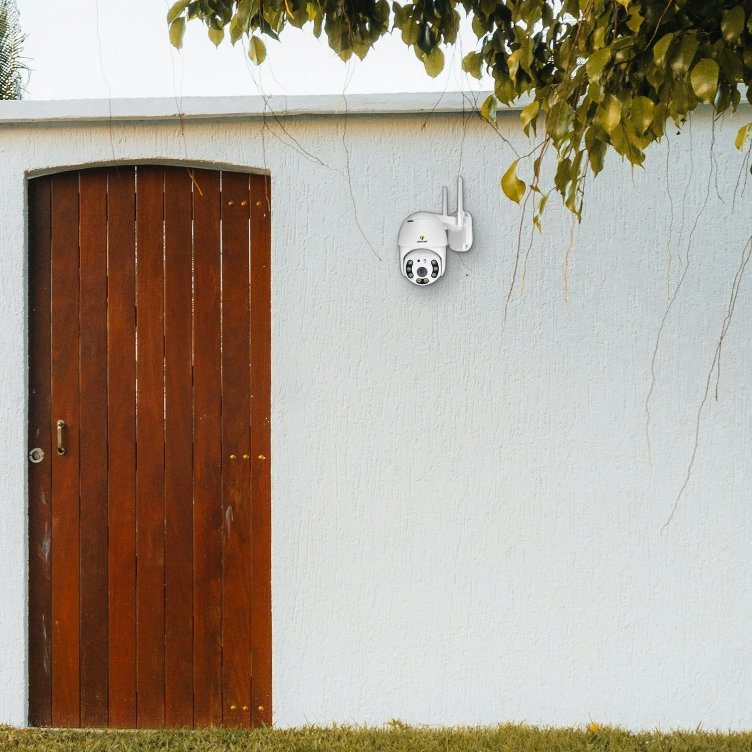 Una cámara de seguridad blanca montada en una pared blanca junto a una puerta de madera.