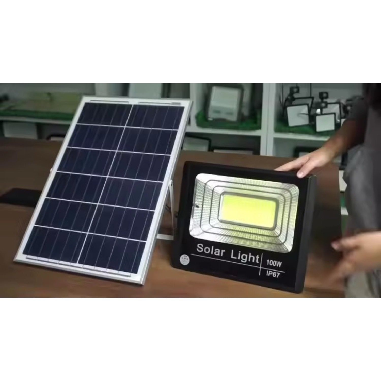 Un pannello solare e una lampada solare IP67 da 100W sono su un tavolo di legno.