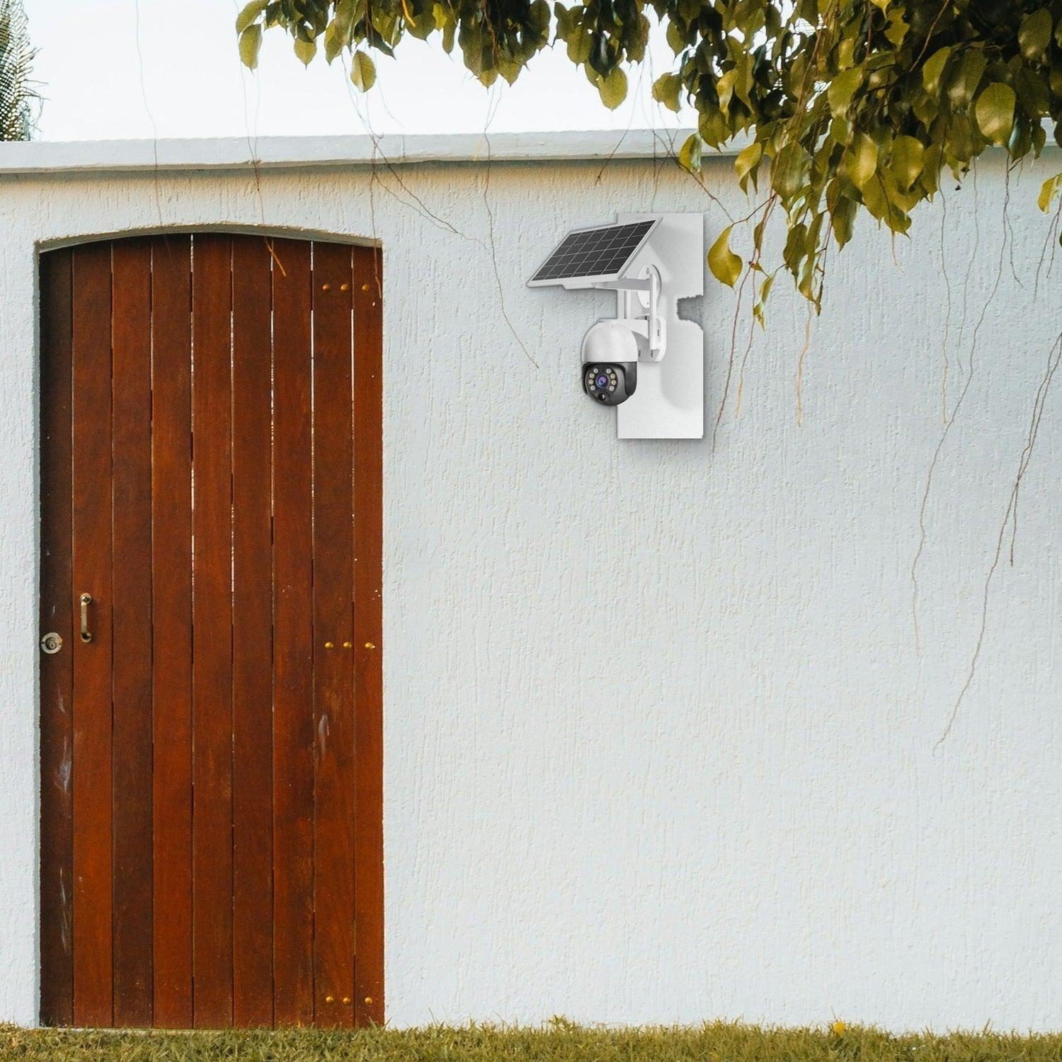 Una cámara de seguridad solar está montada en una pared blanca junto a una puerta de madera.