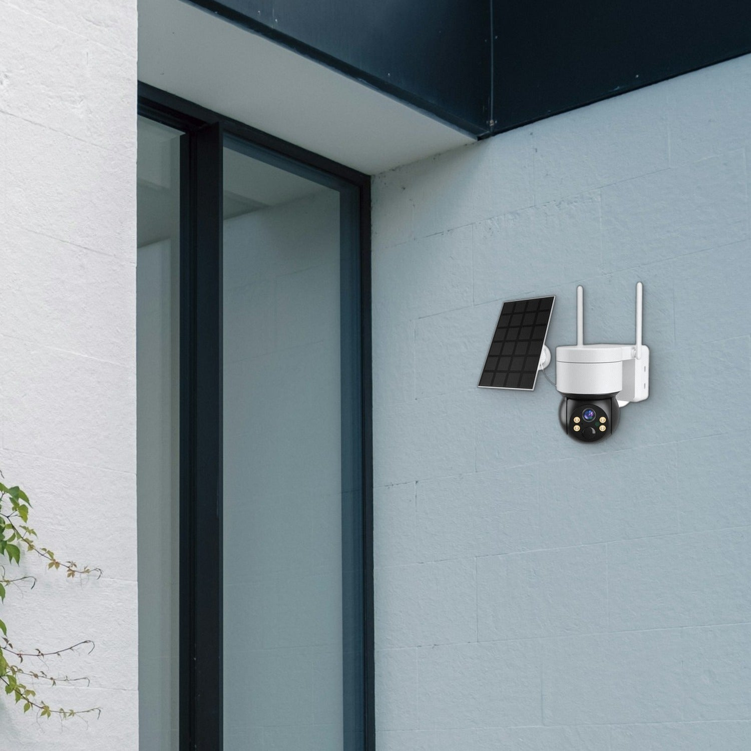 Una cámara de seguridad blanca con panel solar está montada en una pared azul junto a una puerta de vidrio.