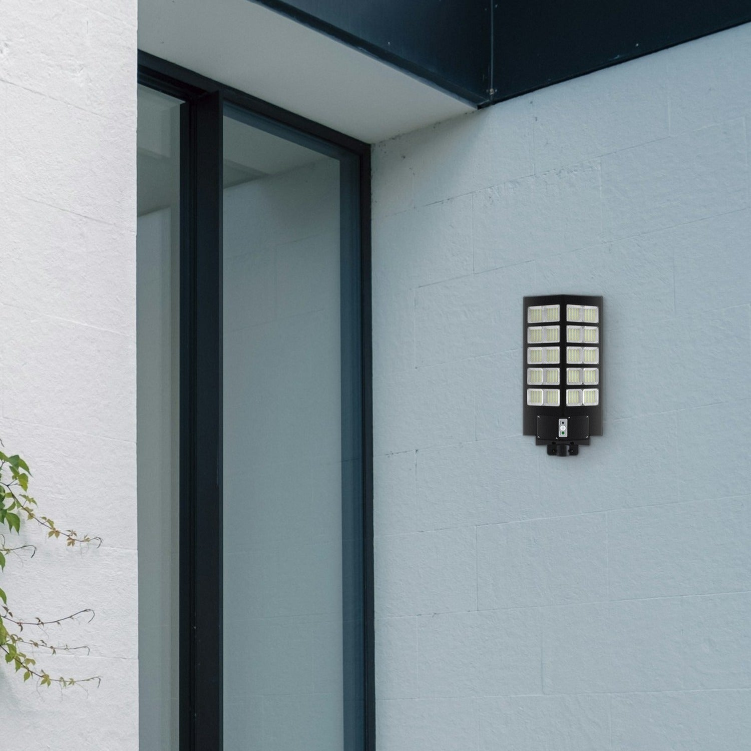 Una lámpara de pared LED negra está montada en la pared de una casa clara junto a una puerta de vidrio.