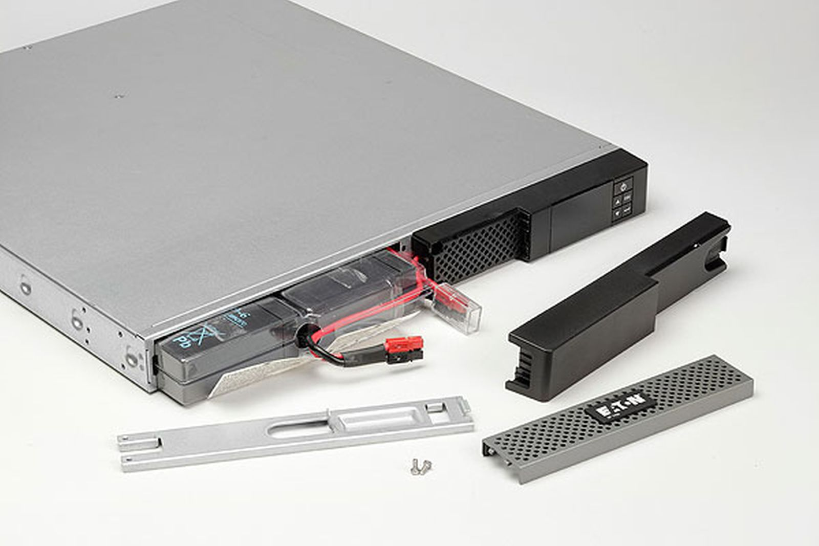 UPS device with opened battery compartment, removed front panels, and small screws.