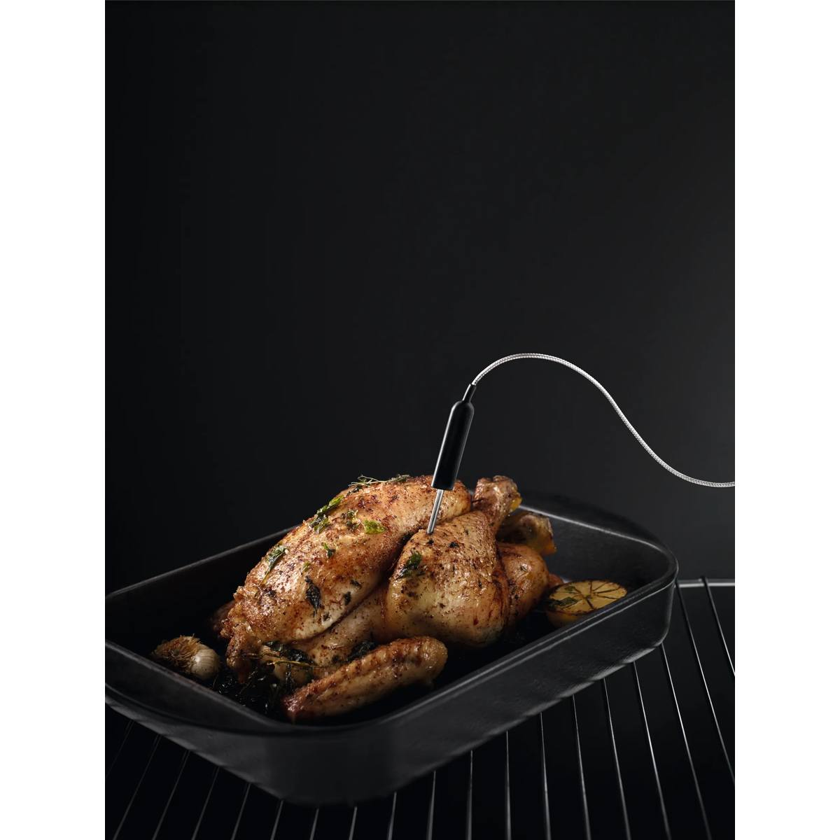 Un pollo arrosto in una teglia con un termometro per carne su una griglia del forno.