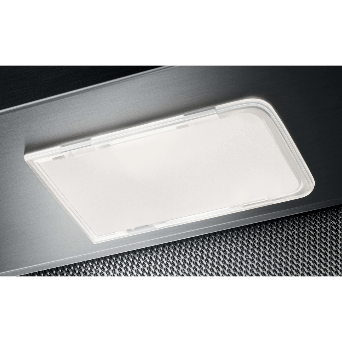 Primer plano de una luz LED rectangular encendida en una campana extractora sobre un filtro de metal.