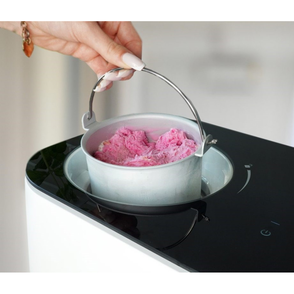 Eine Hand hält den Metallbehälter einer Eismaschine mit rosa Eis gefüllt über das Gerät.