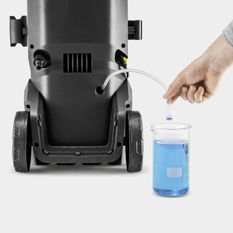 Una mano posiziona un tubo trasparente di un'idropulitrice nera in un becher pieno di liquido blu.
