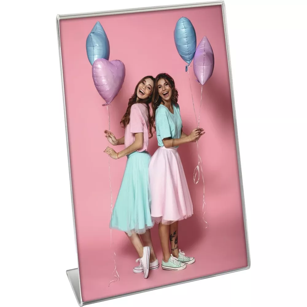 Zwei lächelnde Frauen in bunten Röcken halten Luftballons vor rosa Hintergrund in einem Silberrahmen.