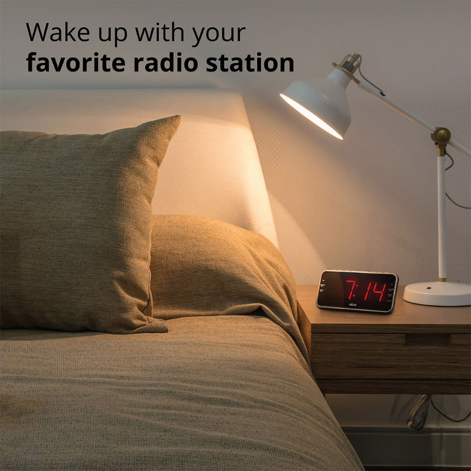 Un comodino con lampada e radiosveglia accanto a un letto rifatto.