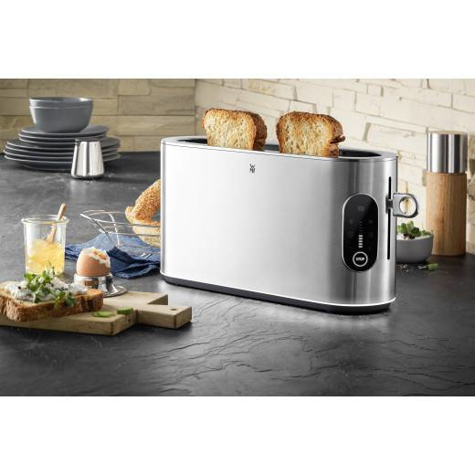 Ein Edelstahltoster mit zwei Toasts auf einer Kcheanrichte mit Frhstcksartikeln.