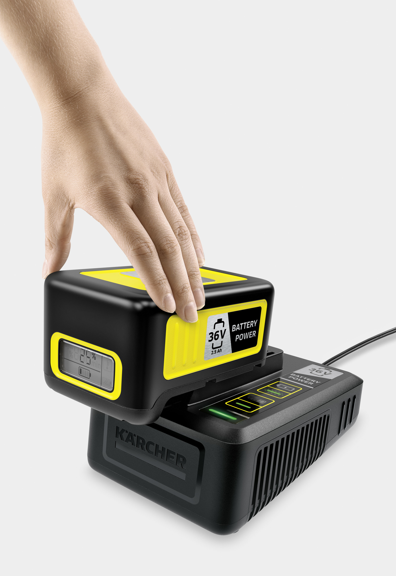Ręka wkłada żółto-czarną baterię Karcher 36V do ładowarki.