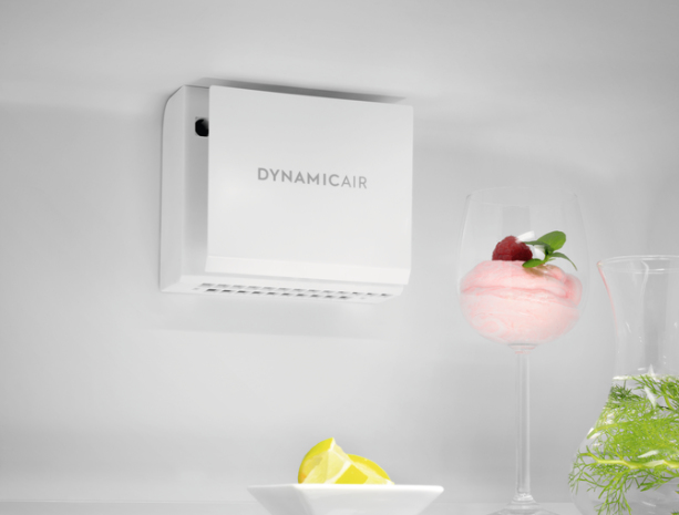 Ein weißes DynamicAir-Gerät an einer Wand, daneben ein Glas mit rosa Dessert und Zitronenscheiben.