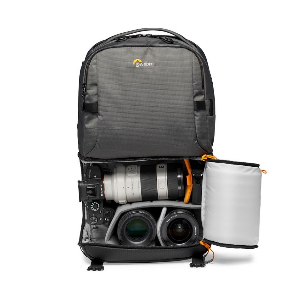 Grauer Lowepro Kamerarucksack mit offener unterer Tasche, die eine Kamera und zwei Objektive enthält.