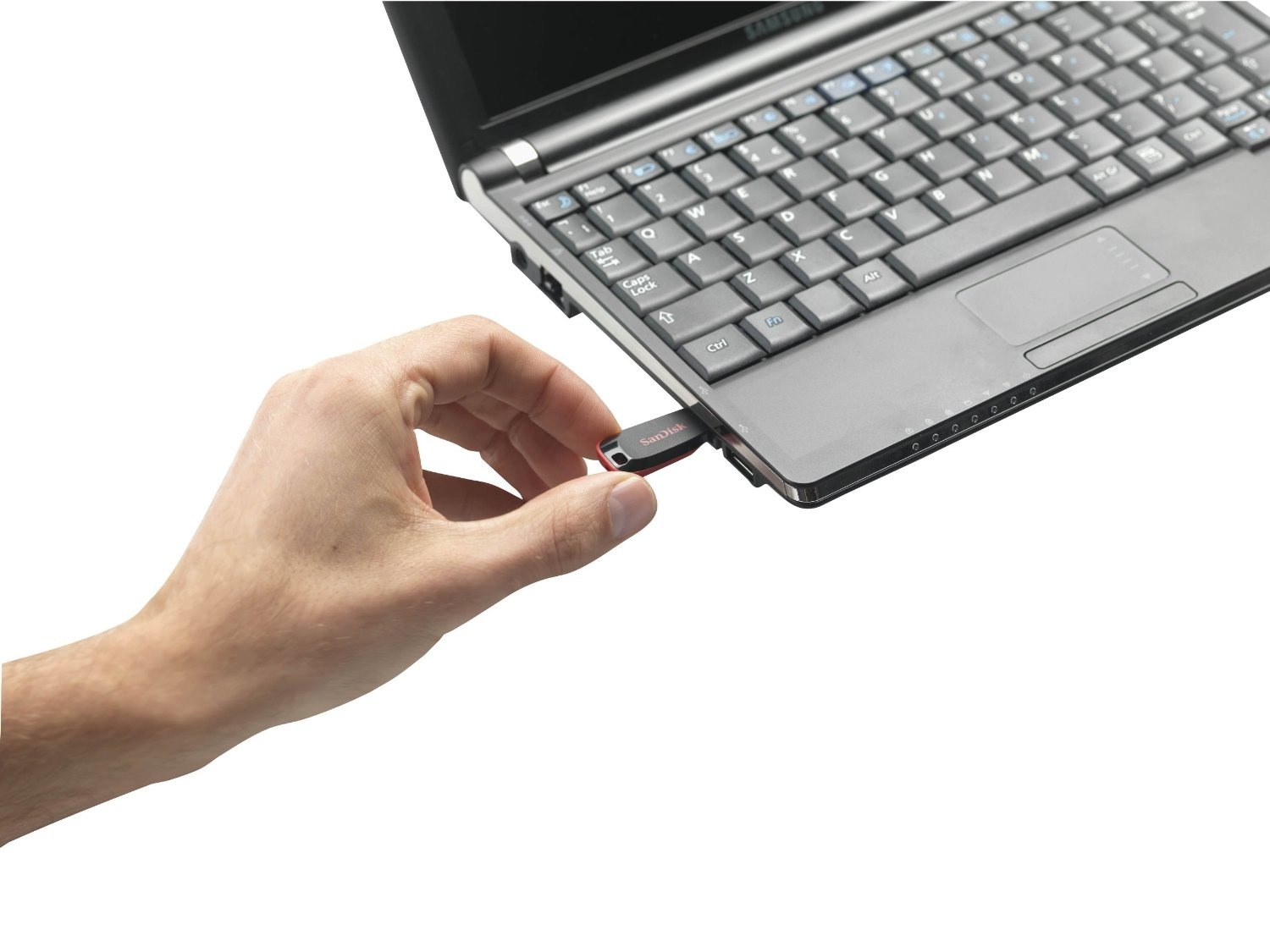 A hand inserts a red SanDisk USB flash drive into a laptop's USB port.
