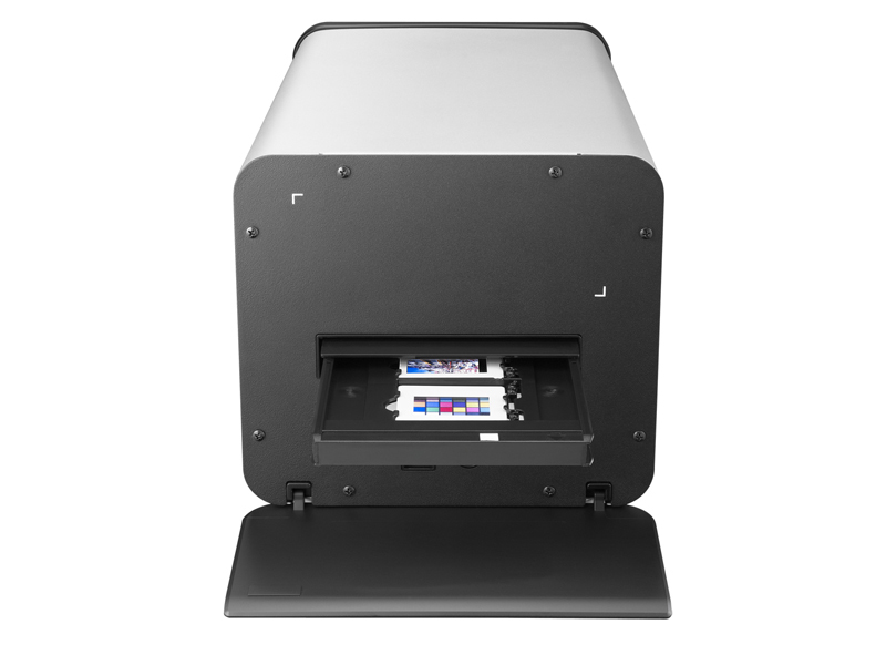 Un dispositivo elettronico argento e nero con un vassoio aperto e tabelle di prova colore all'interno su sfondo bianco.