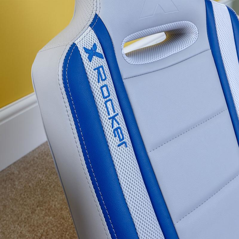 Nahaufnahme eines weiß-blauen X Rocker Gaming-Stuhls mit gesticktem Logo und Mesh-Detail.