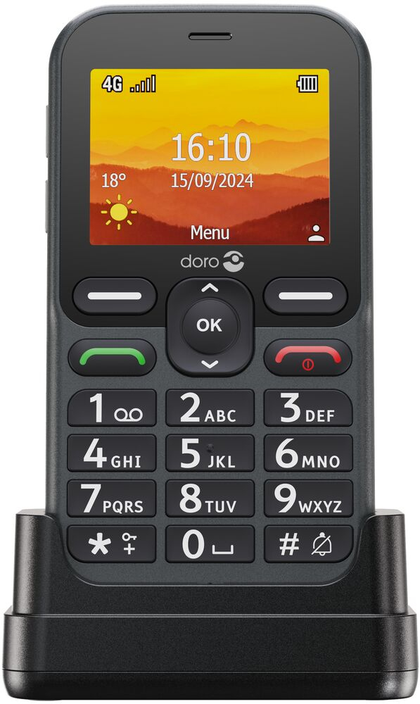 Un teléfono básico Doro gris en una base de carga, con pantalla a color, botones grandes y fondo de atardecer.
