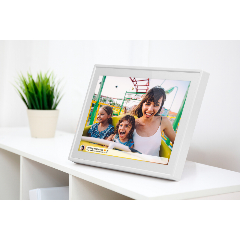 Ein weißer digitaler Bilderrahmen auf einem Regal zeigt eine glückliche Familie in einem Vergnügungspark.