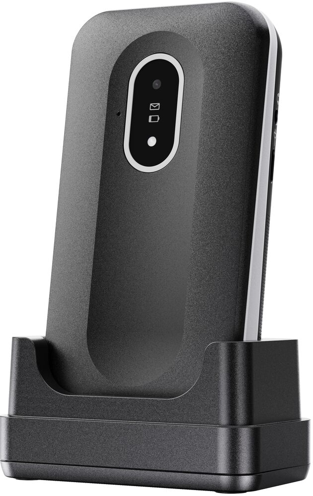 Un cellulare nero si trova verticalmente in una base di ricarica nera su sfondo bianco.