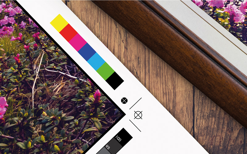 Scheda di prova di stampa con scala colori vicino a una cornice di legno.
