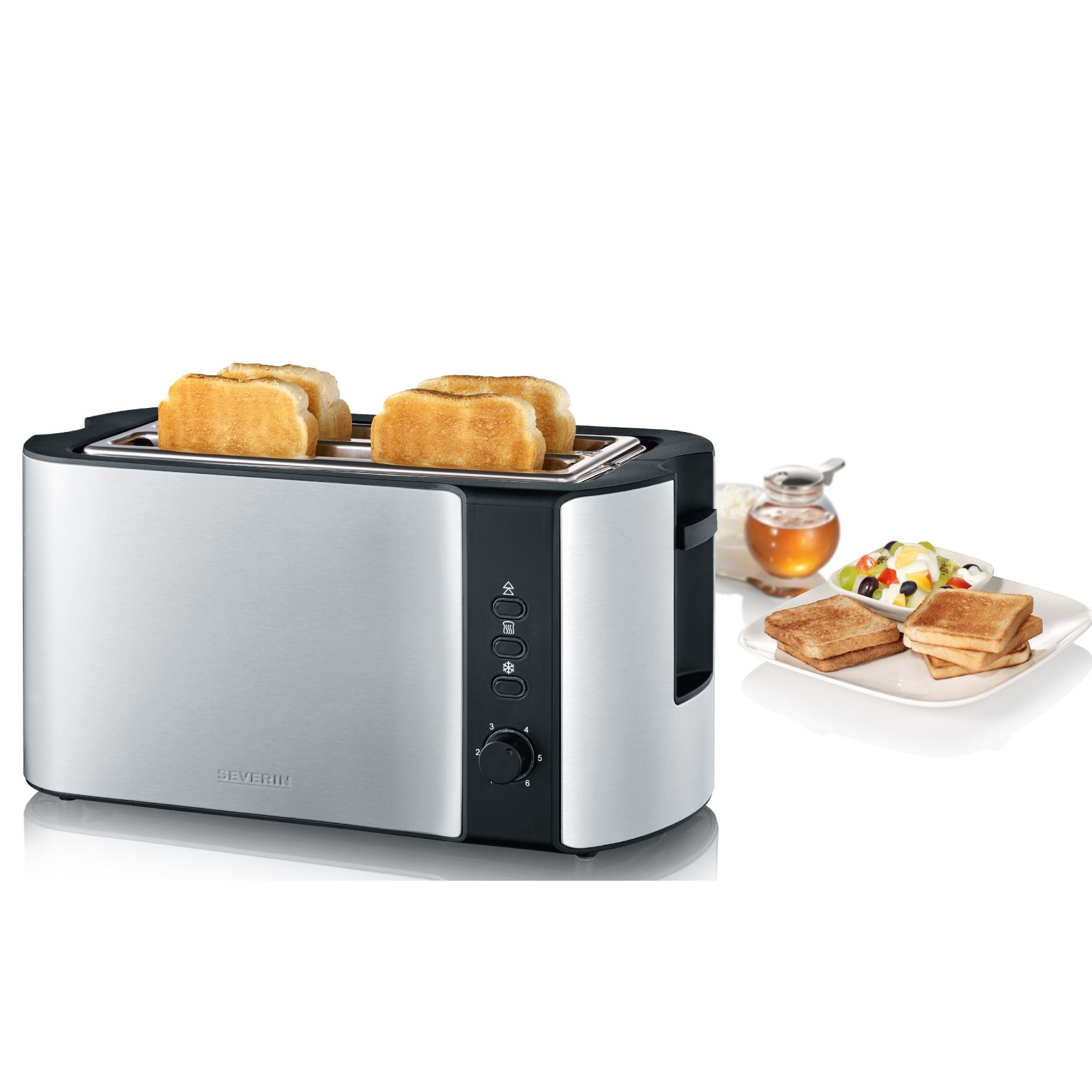 Ein langer Edelstahl-Toaster mit vier Scheiben Toast, daneben Teller mit Toast, Obstsalat und Honig.