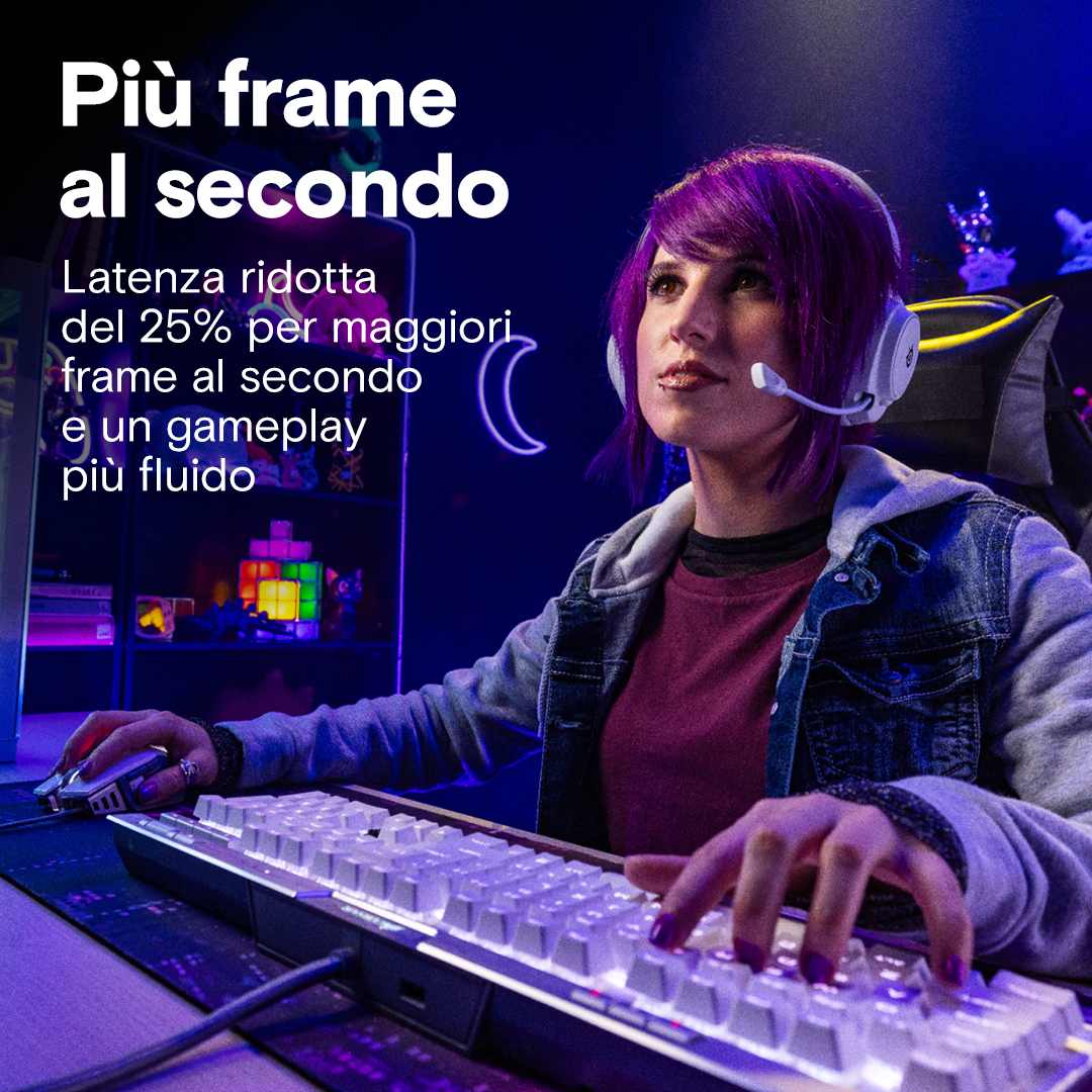 Eine Frau mit lila Haaren und weißen Kopfhörern spielt in einem dunklen Raum an einem PC.
