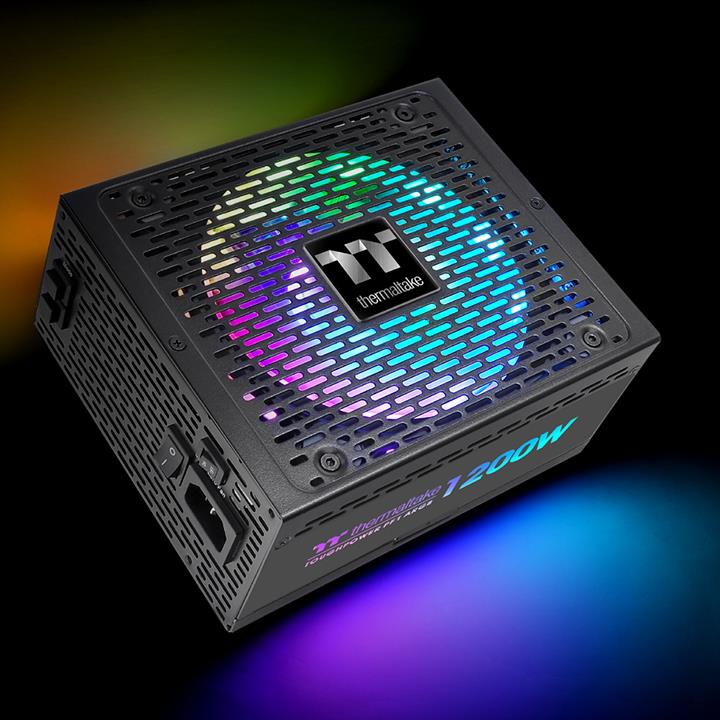 Ein schwarzes Thermaltake 1200W Netzteil mit bunter RGB-Lüfterbeleuchtung, aus einem Winkel vor dunklem Hintergrund.