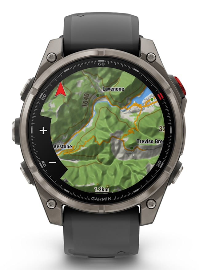 A Garmin smartwatch with a gray case and band displays a colorful topographic map on the screen.